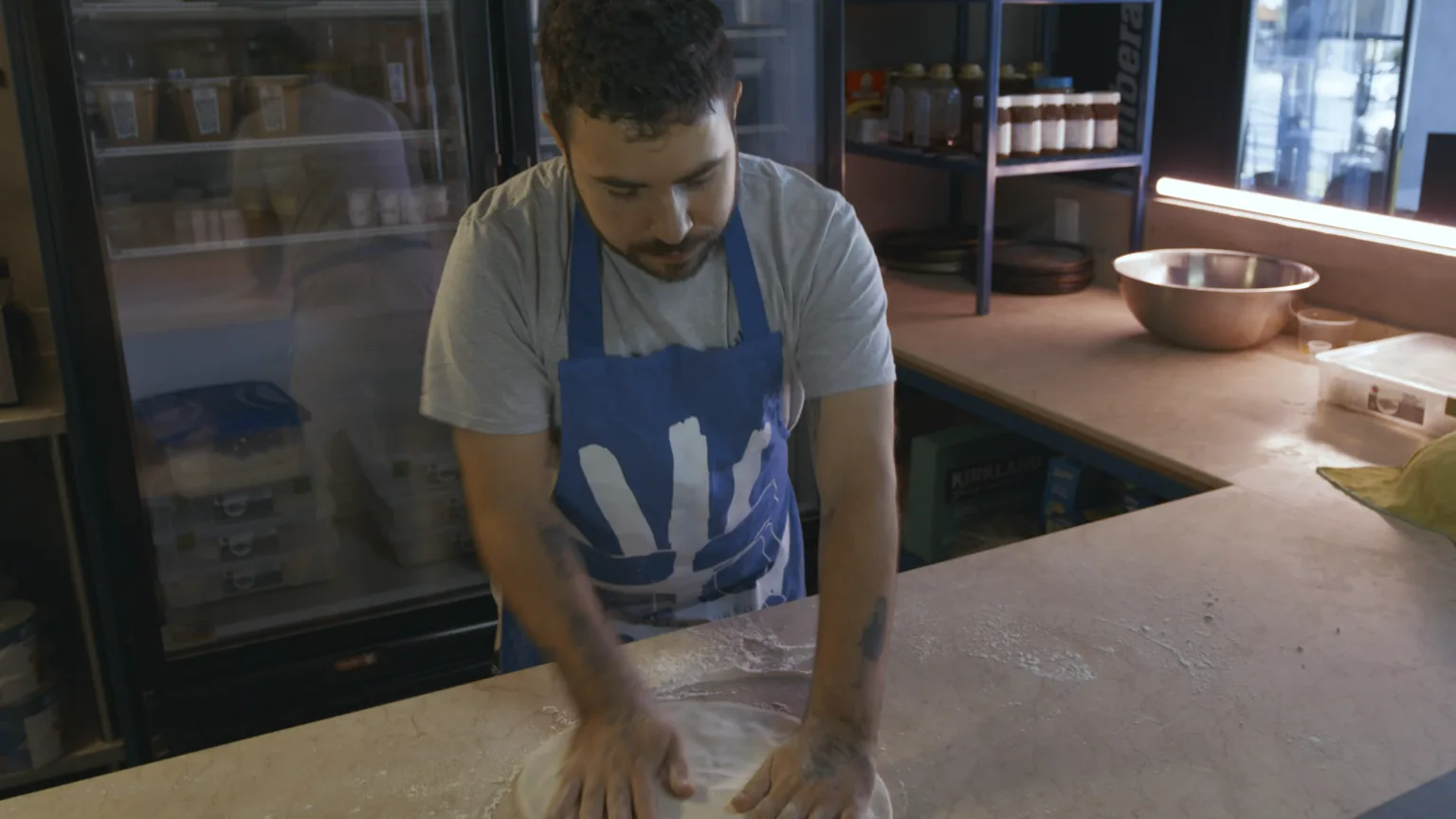 Un restaurateur travaille une pâte à pizza dans sa cuisine