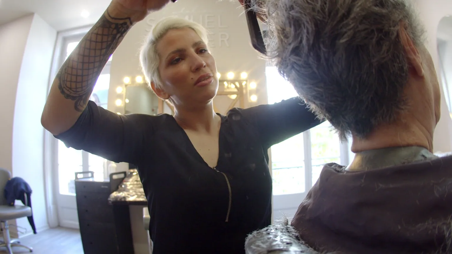 Coiffeuse au travail dans son salon, devant le miroir